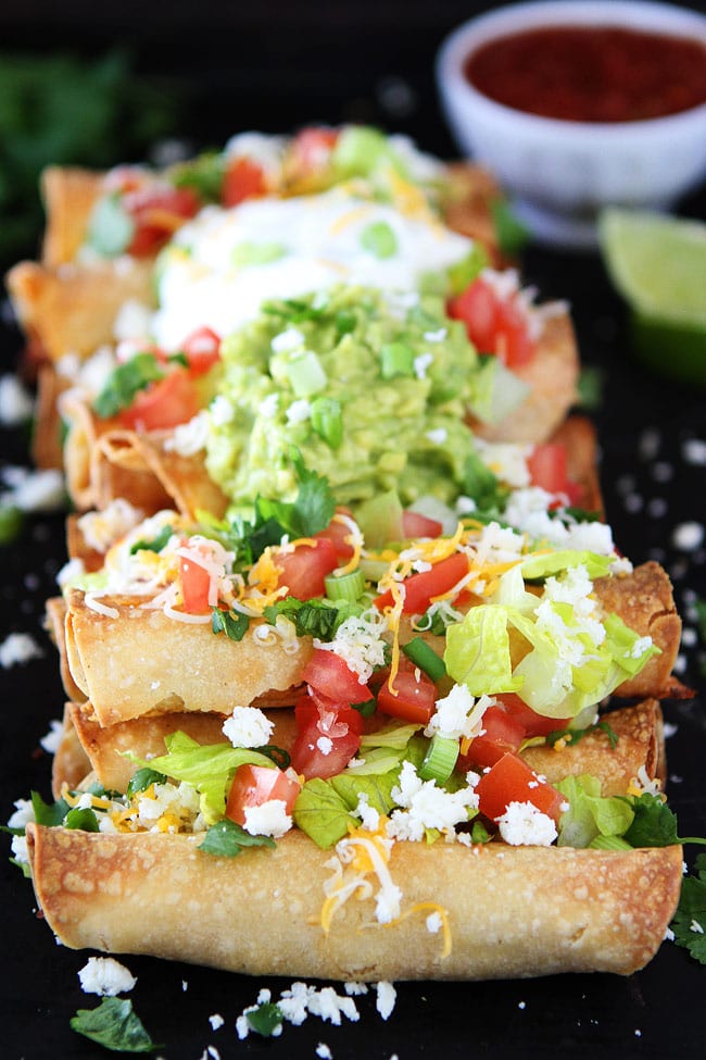 Homemade Taquitos topped with guacamole, cheese and tomato.