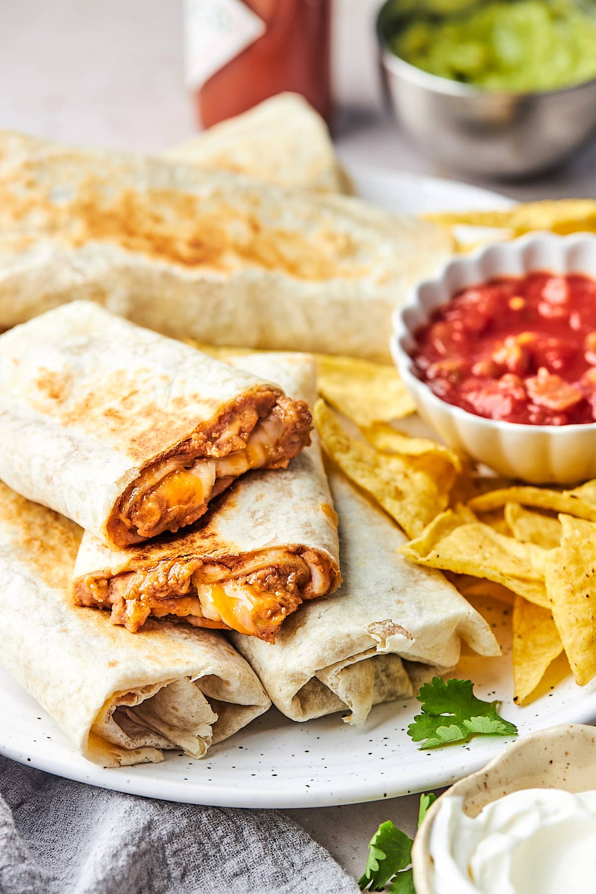 bean and cheese burritos with chips and salsa on plate. 