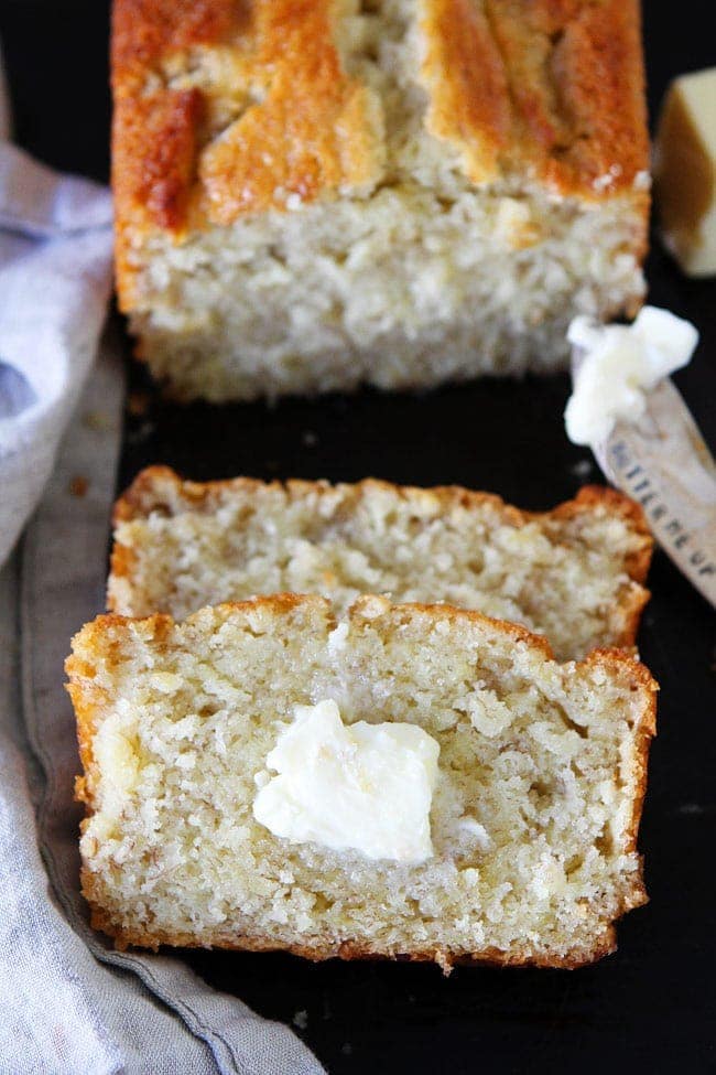 Buttermilk Banana Bread loaf sliced with butter. 