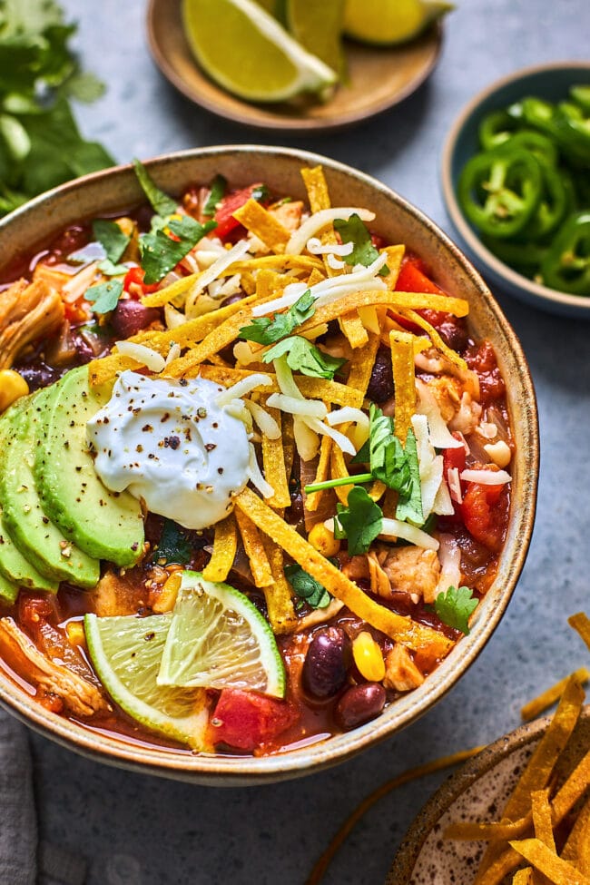 chicken tortilla soup in bowl with toppings.