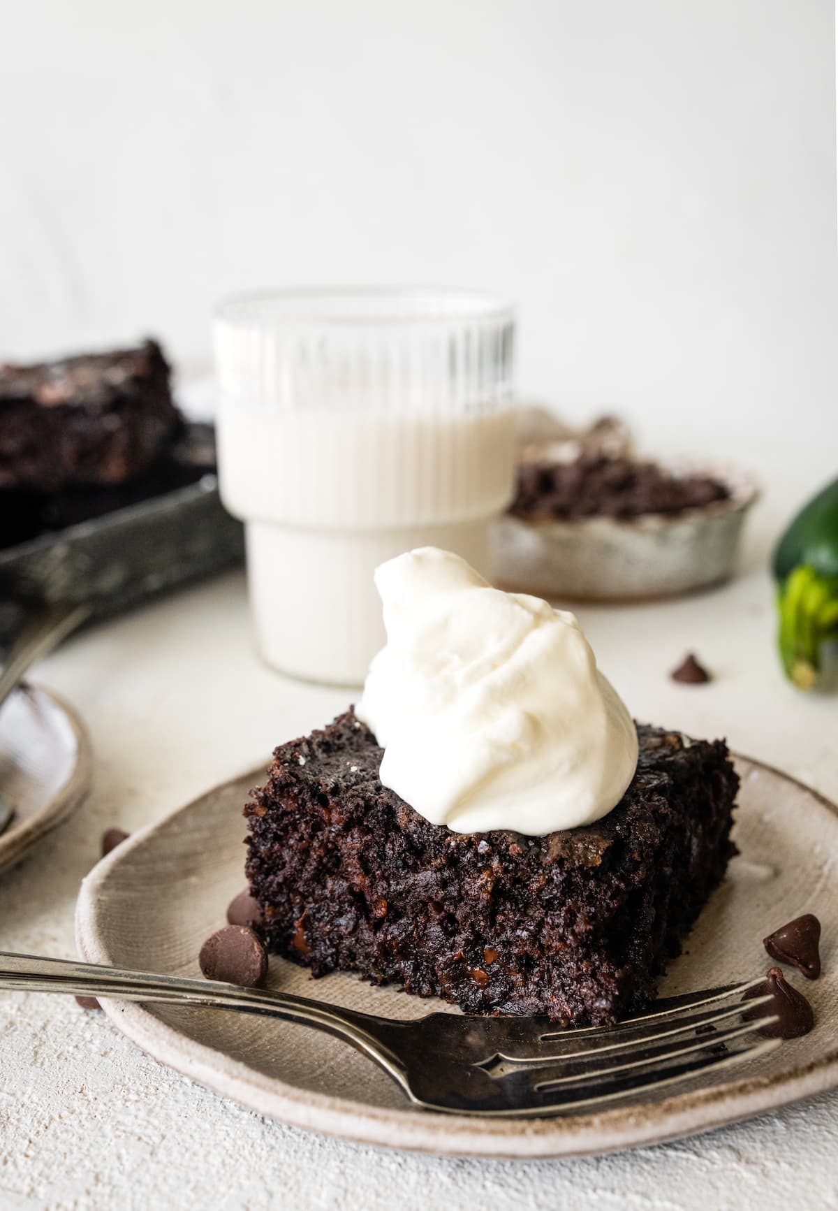 piece of chocolate zucchini snack cake with whipped cream on plate with fork. 