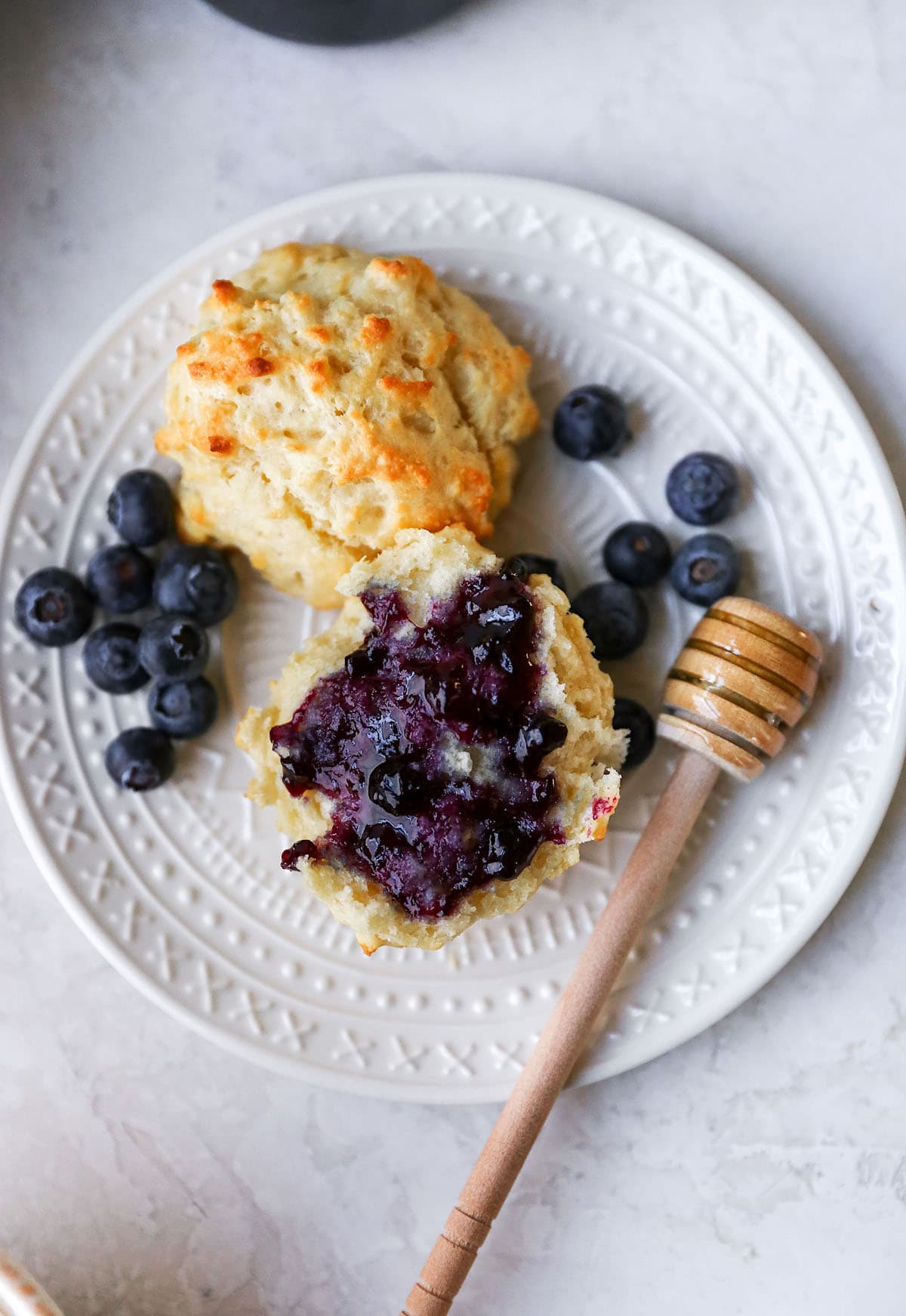 Drop Biscuits cut in half with blueberry jam and honey on plate. 