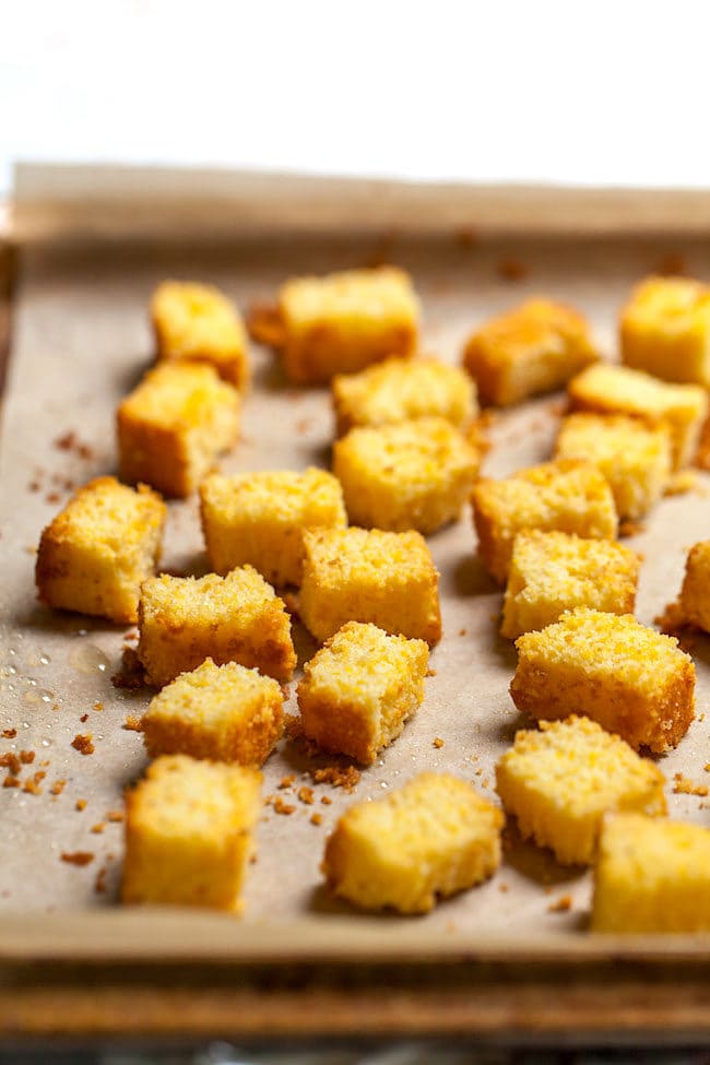 cornbread croutons on baking sheet with parchment paper. 